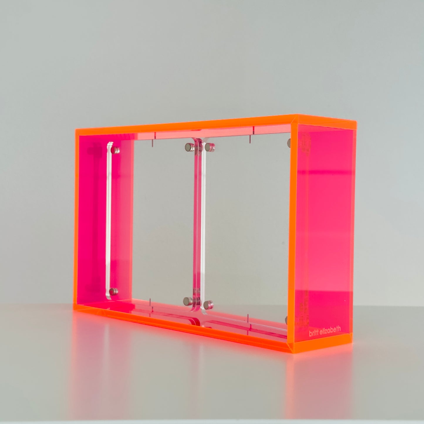 Neon pink transparent photo frame on a gray background