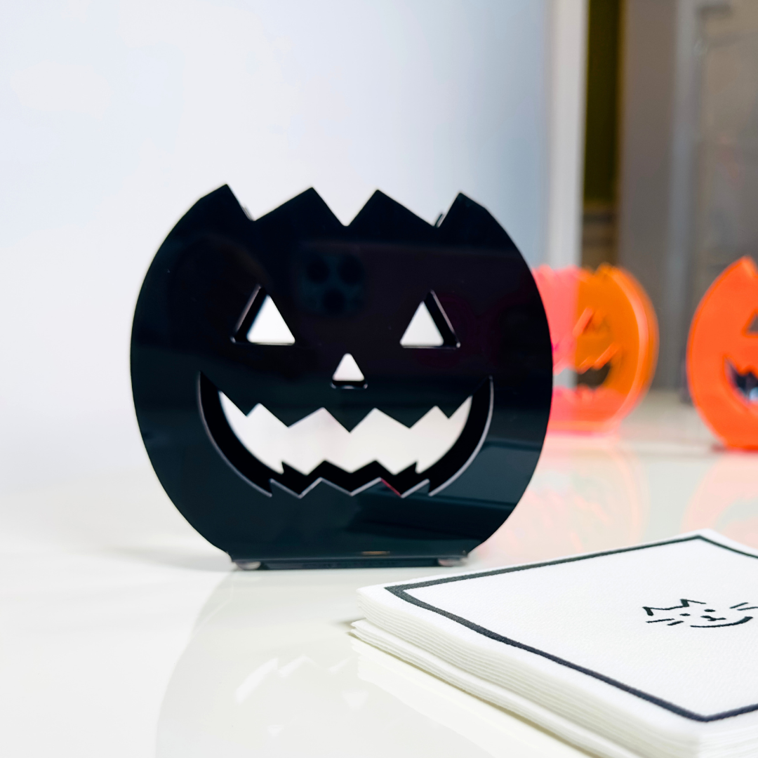 Black jack-o'-lantern-shaped container with a face design on a white surface.