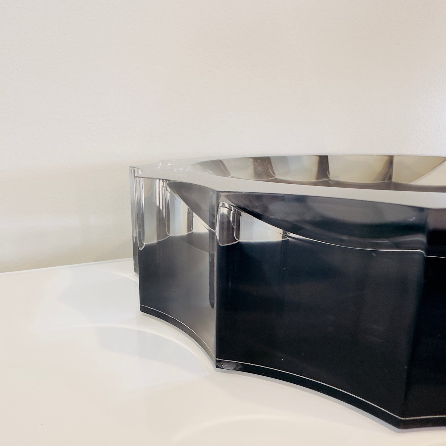 Black and clear acrylic bowl on a white surface with a light gray background