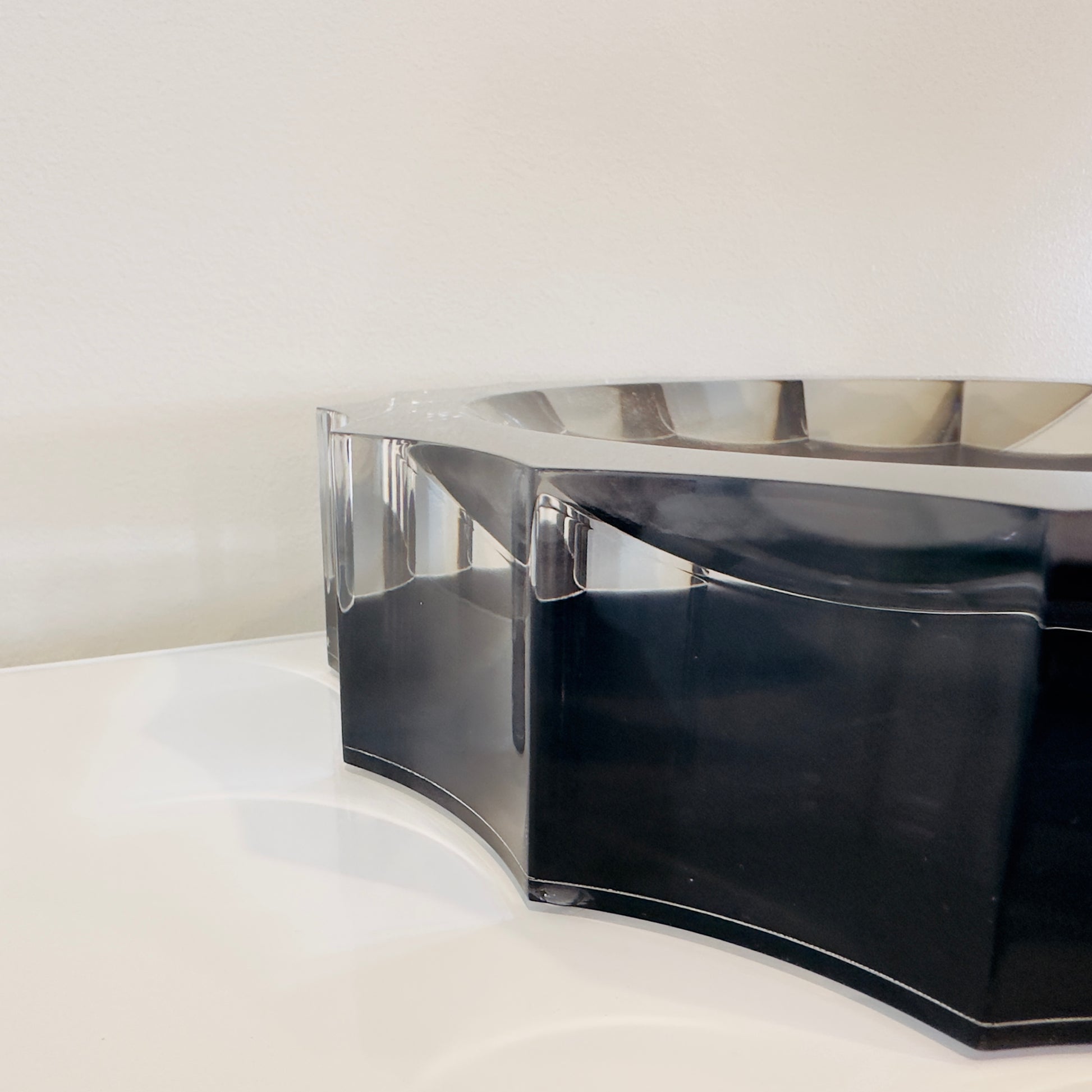 Black and clear acrylic bowl on a white surface with a light gray background