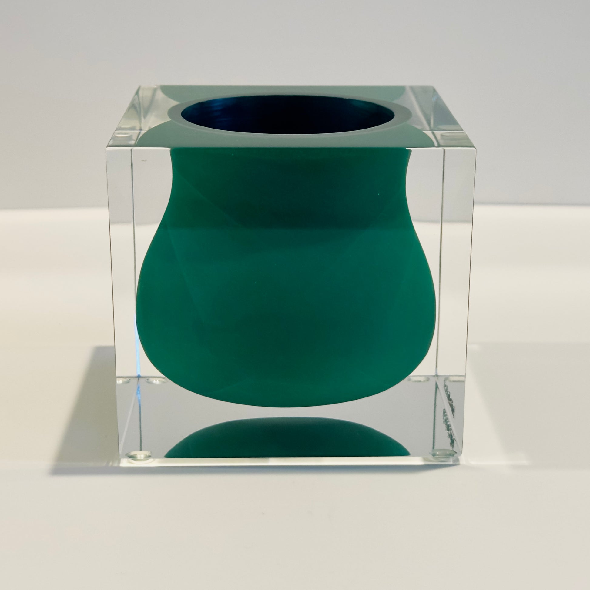 Green vase inside a clear cube on a white background