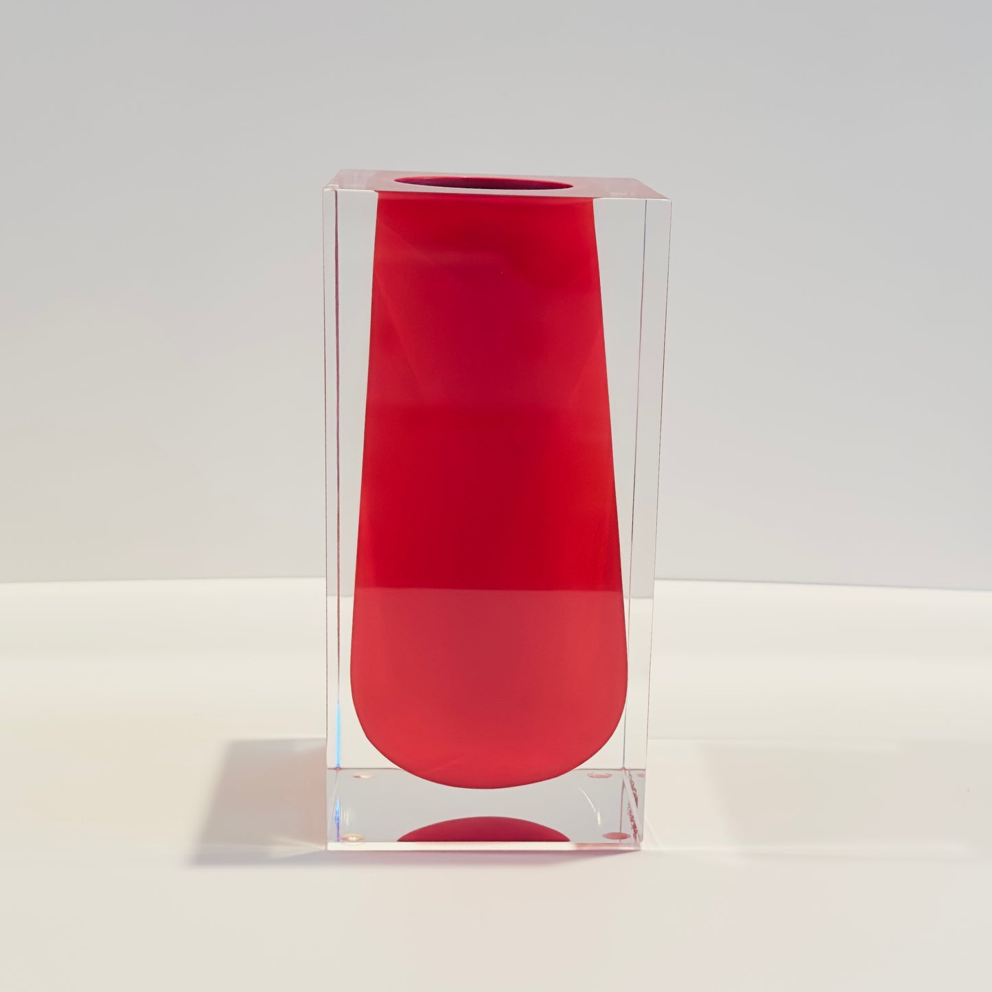 Red cylindrical vase with clear sides on a white background