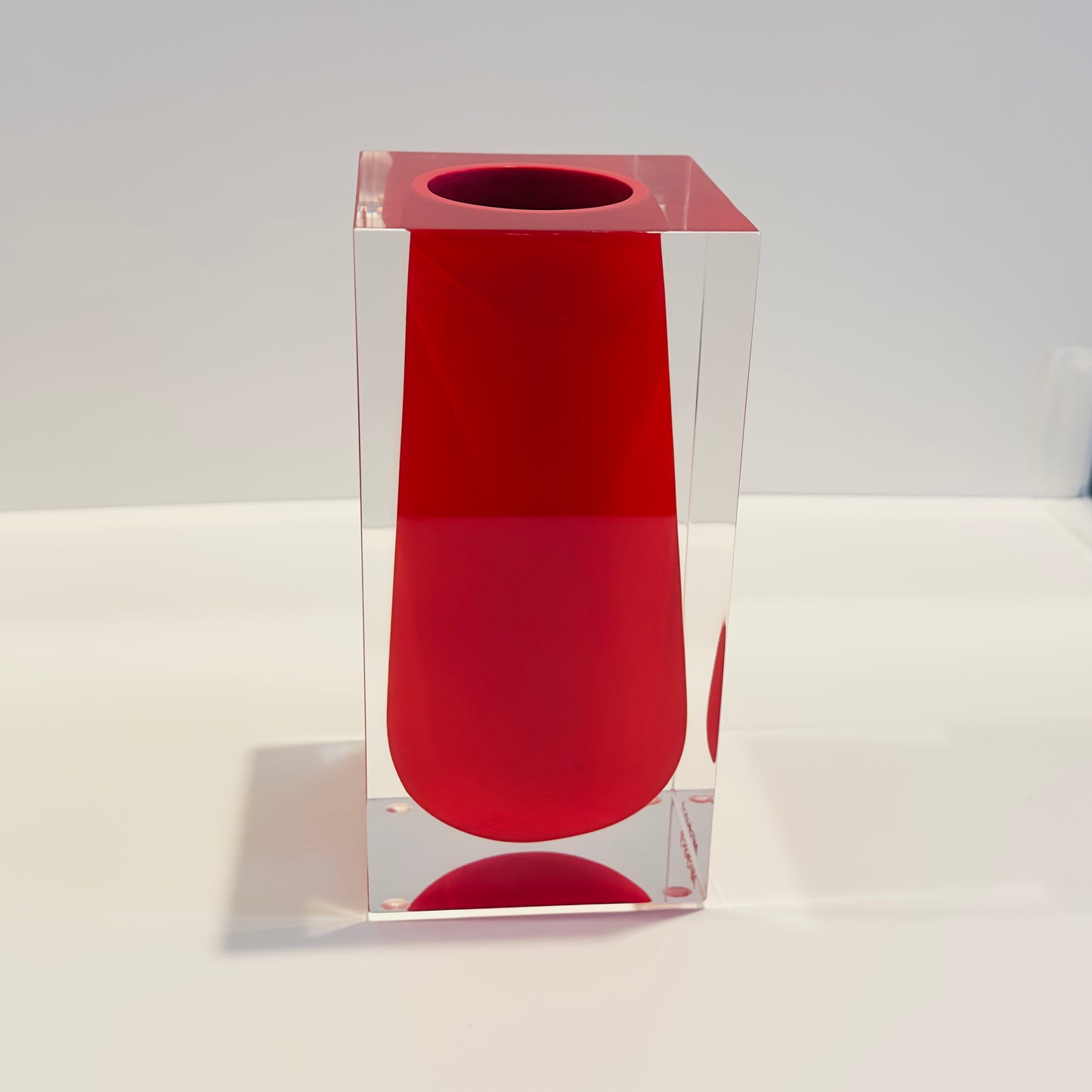 Red cylindrical object with a clear square base on a white background