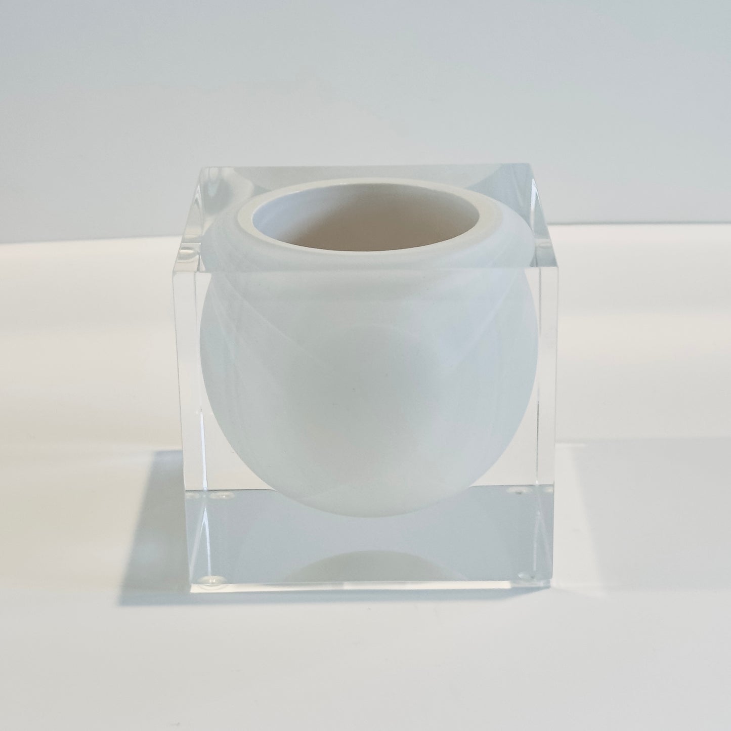 White acrylic vase inside a clear acrylic cube on a white background