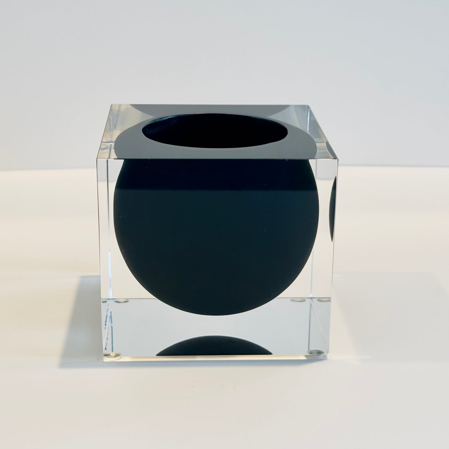 Clear cube with a black sphere inside on a white background