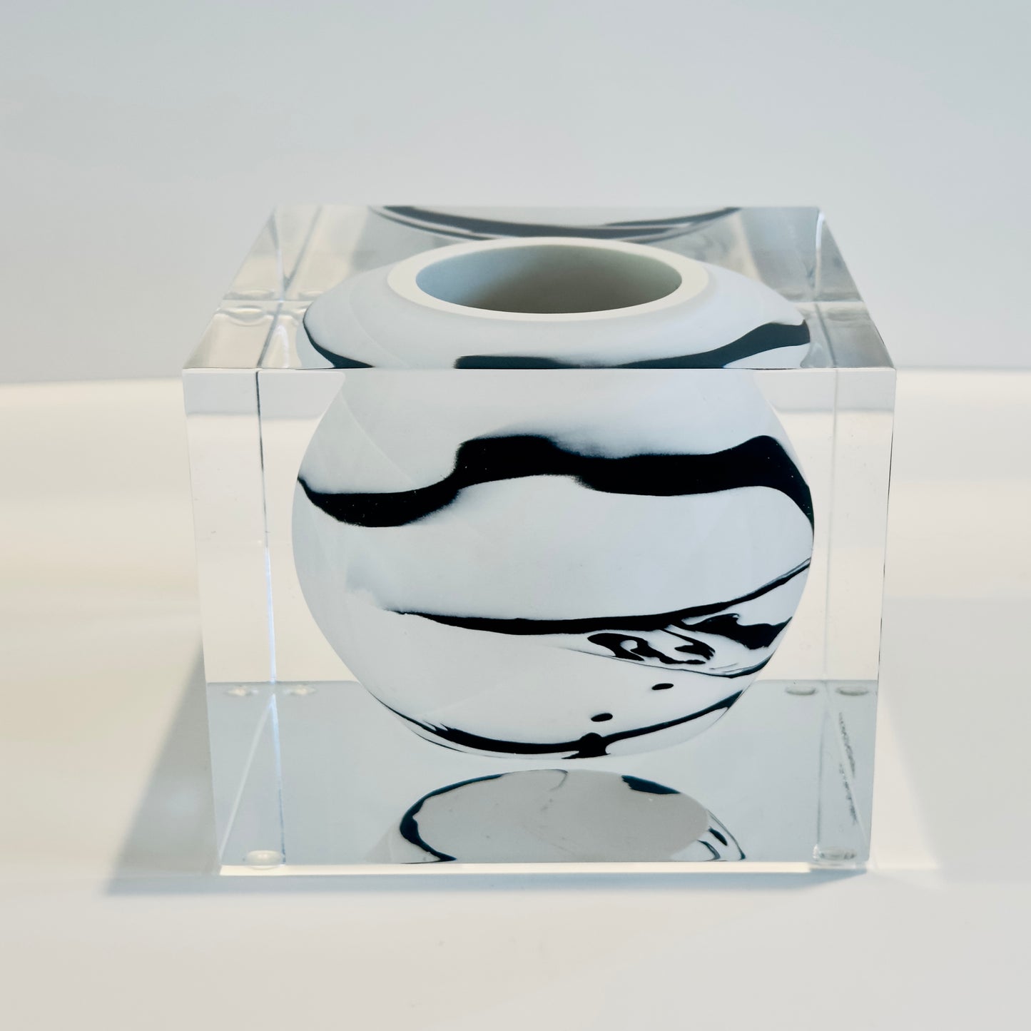 Black and white vase inside a clear glass cube on a white background