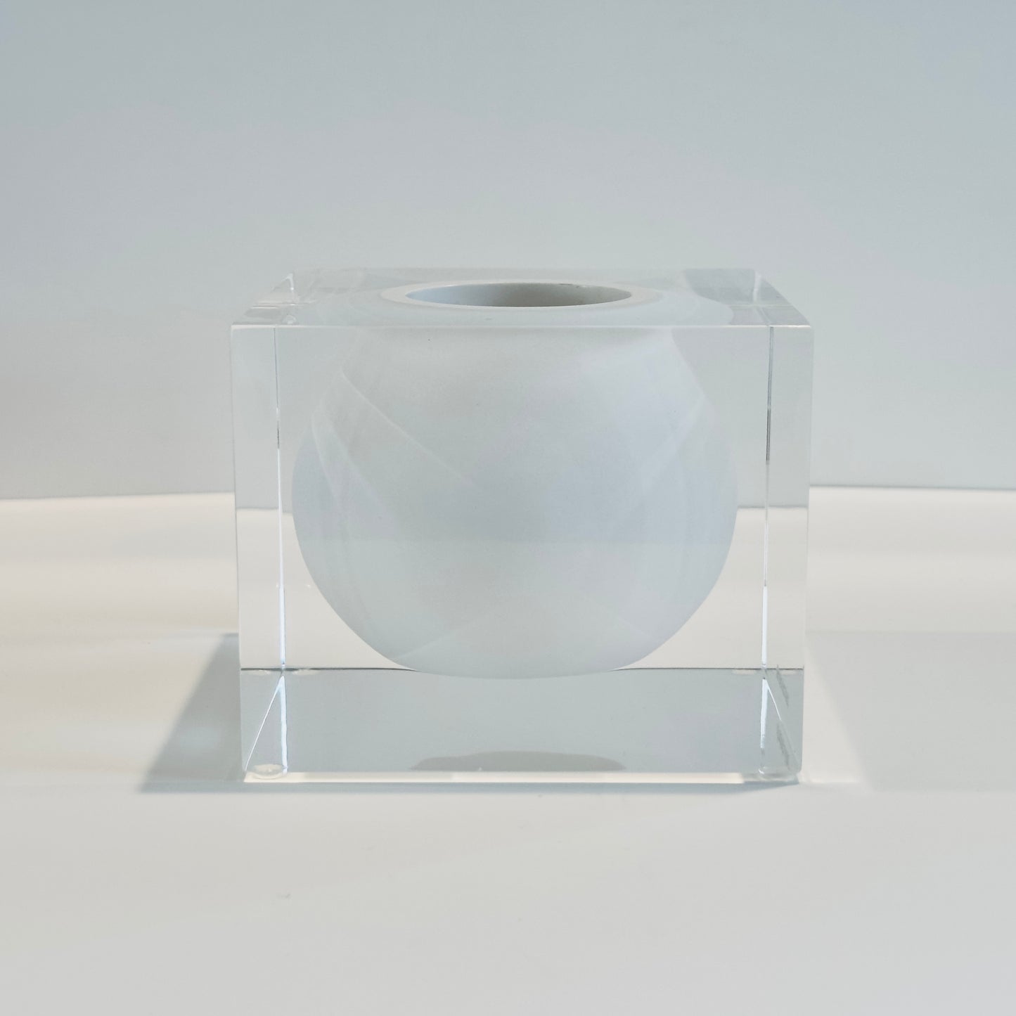 Clear cube with a white sphere inside on a light gray background