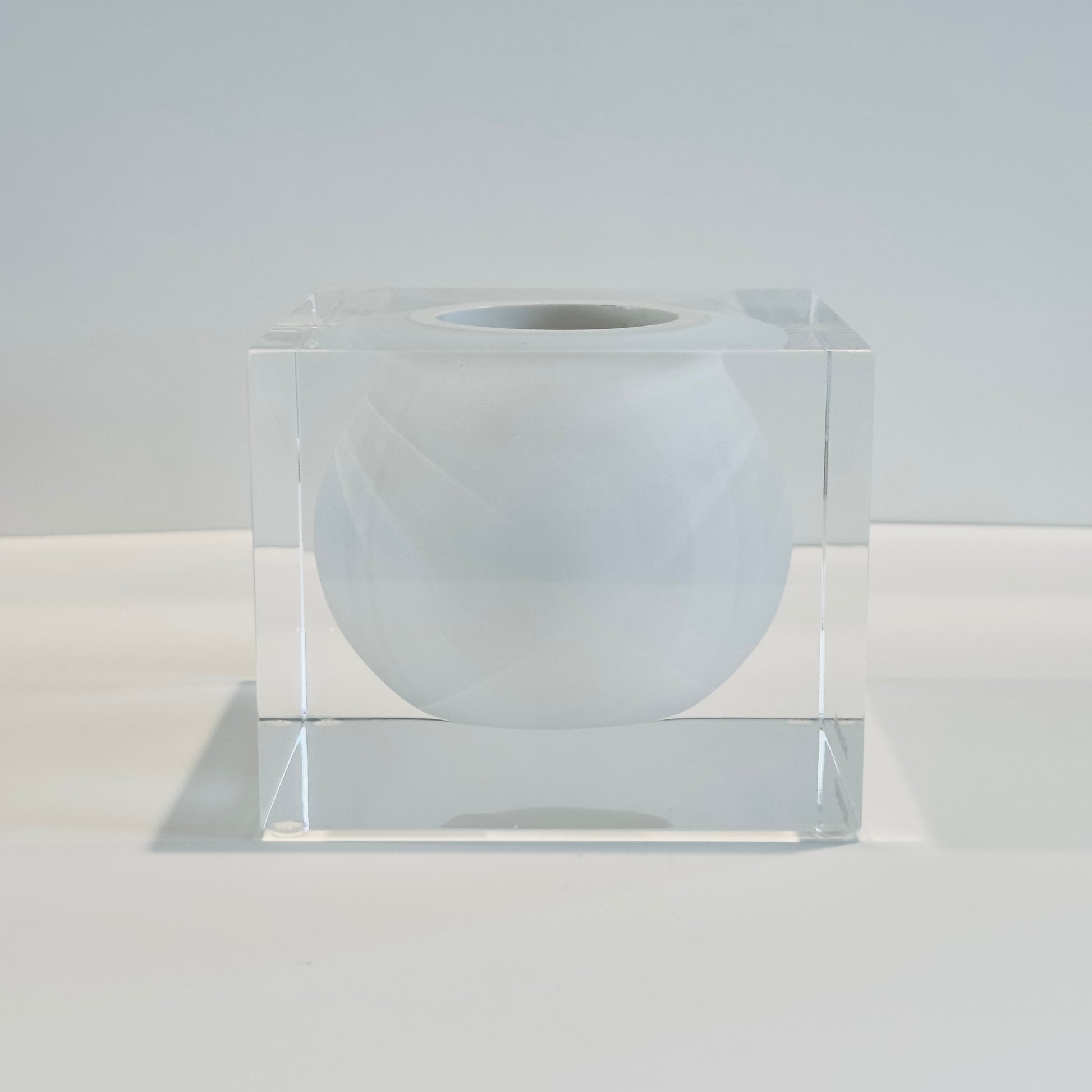 Clear cube with a white sphere inside on a light gray background