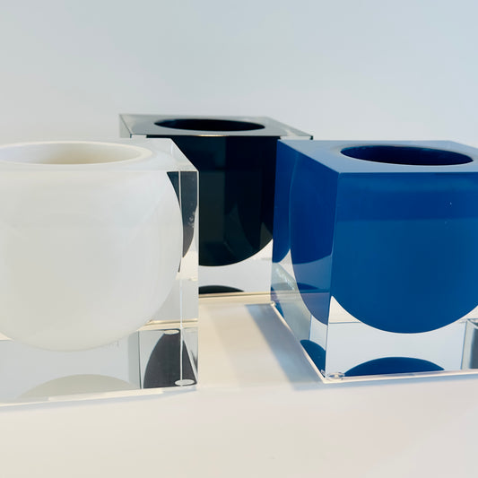 Set of three modern vases in white, black, and blue on a reflective surface with a light gray background.