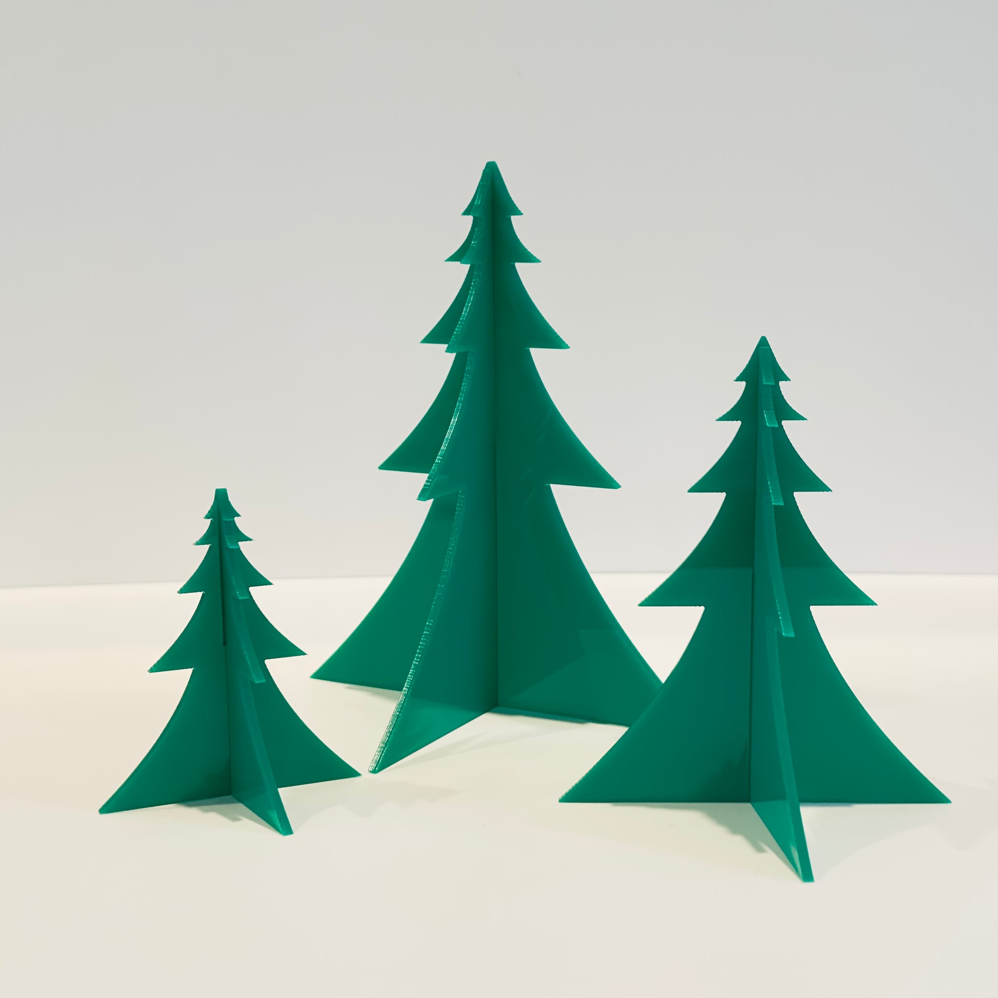 Set of dark green acrylic trees on a white background