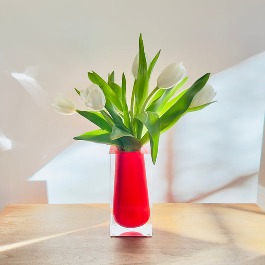 Red vase with white tulips on a wooden surface