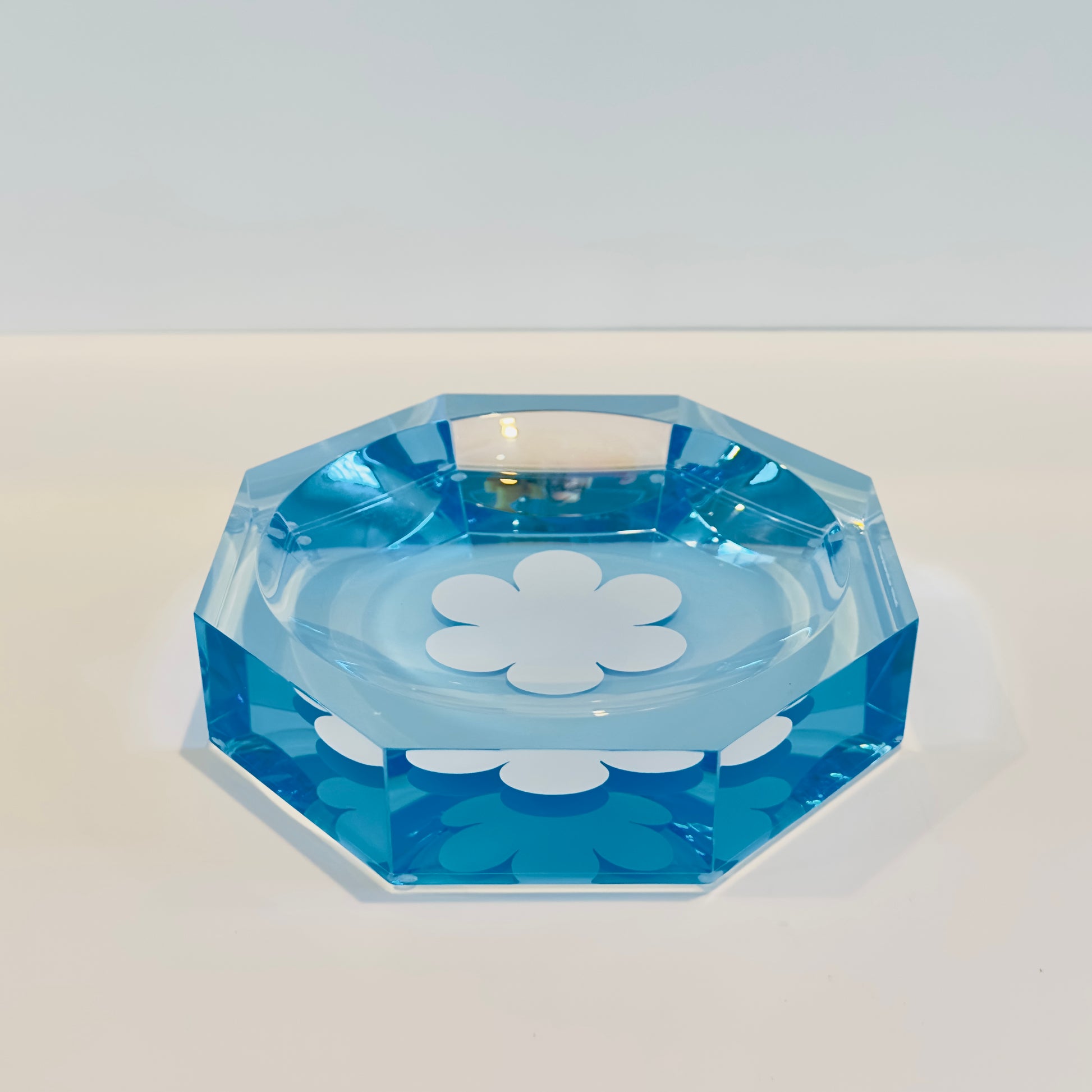 Octagon blue acrylic dish with white floral patterns on a light gray background