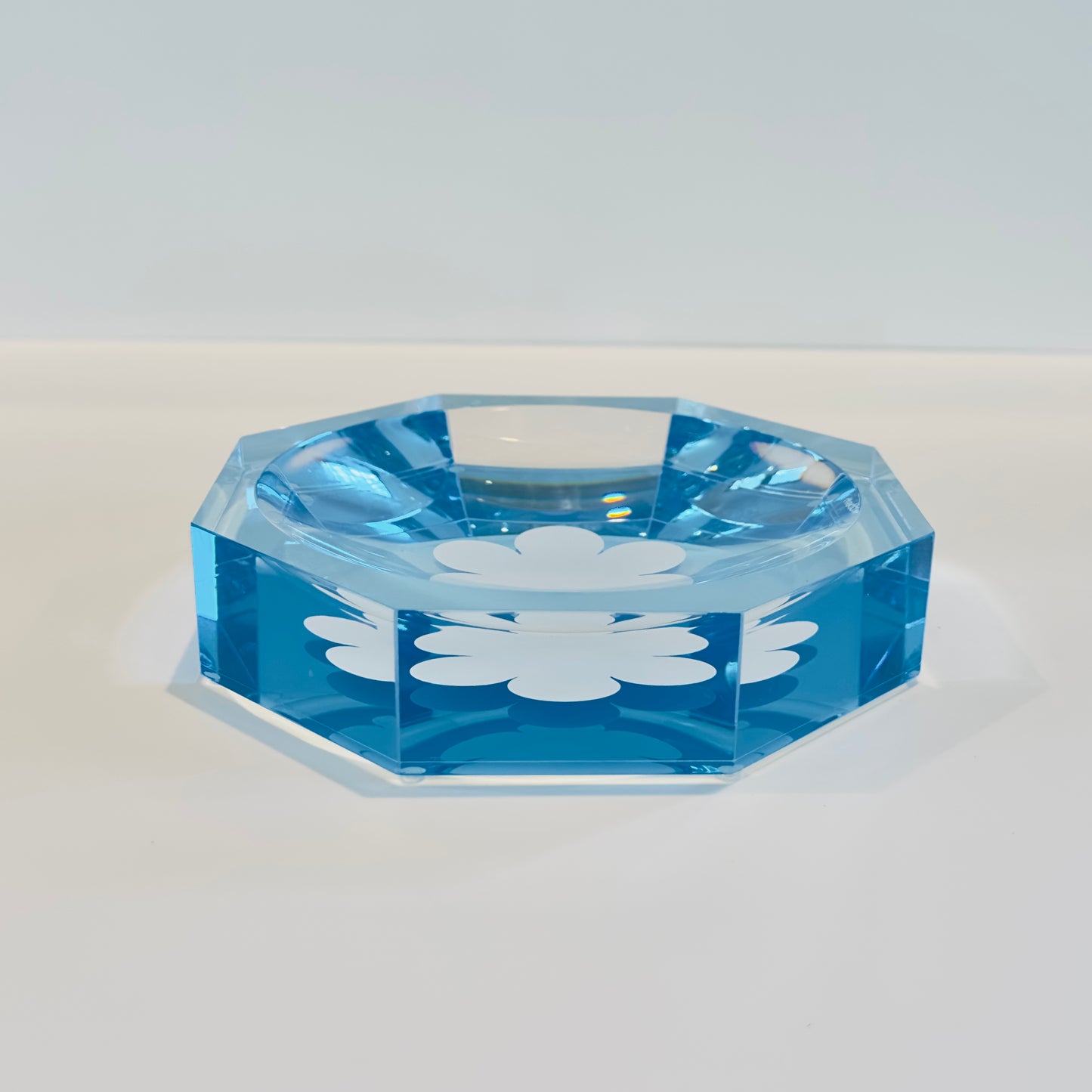 Blue acrylic dish with a white floral design on a light gray background