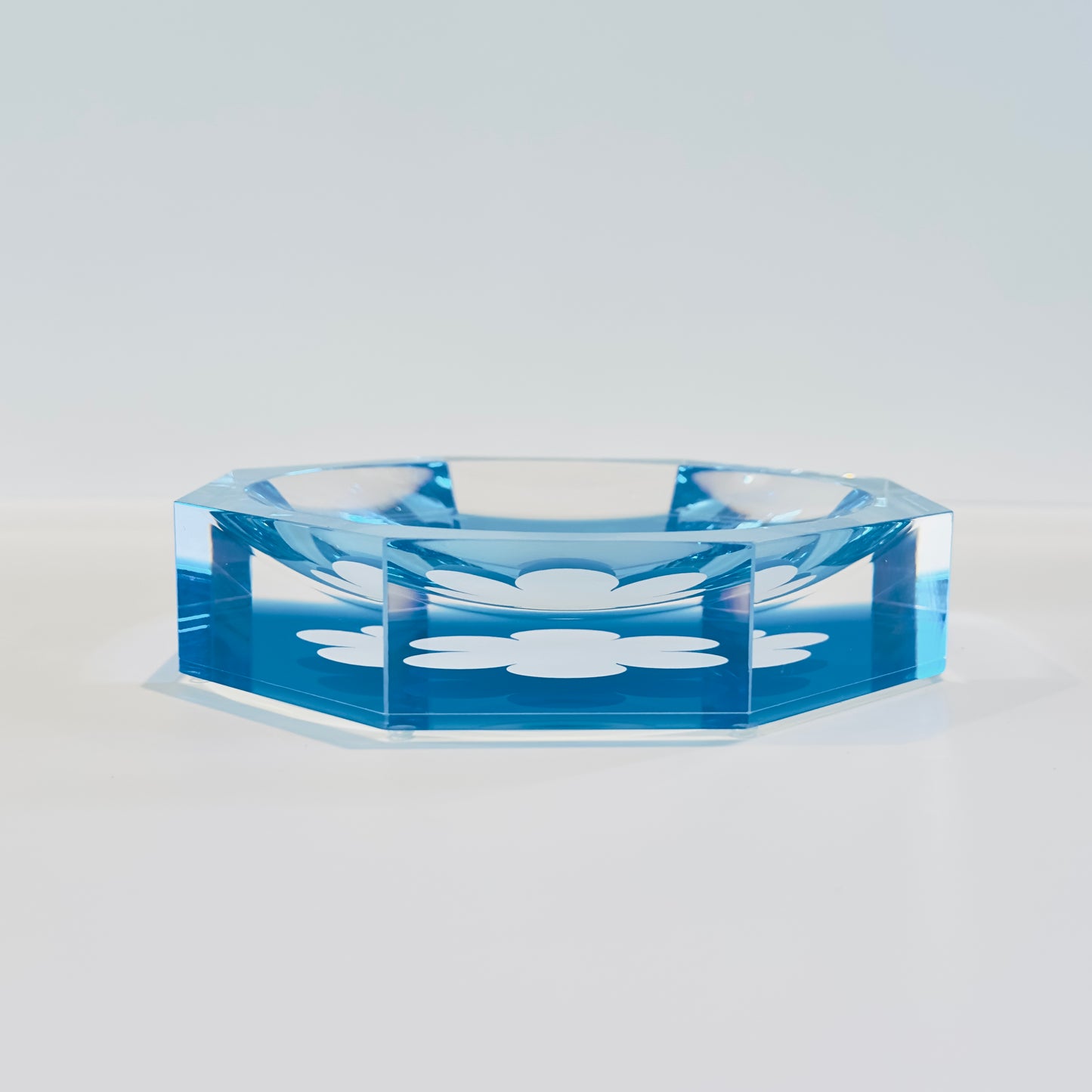 Blue acrylic bowl with floral design on a light gray background