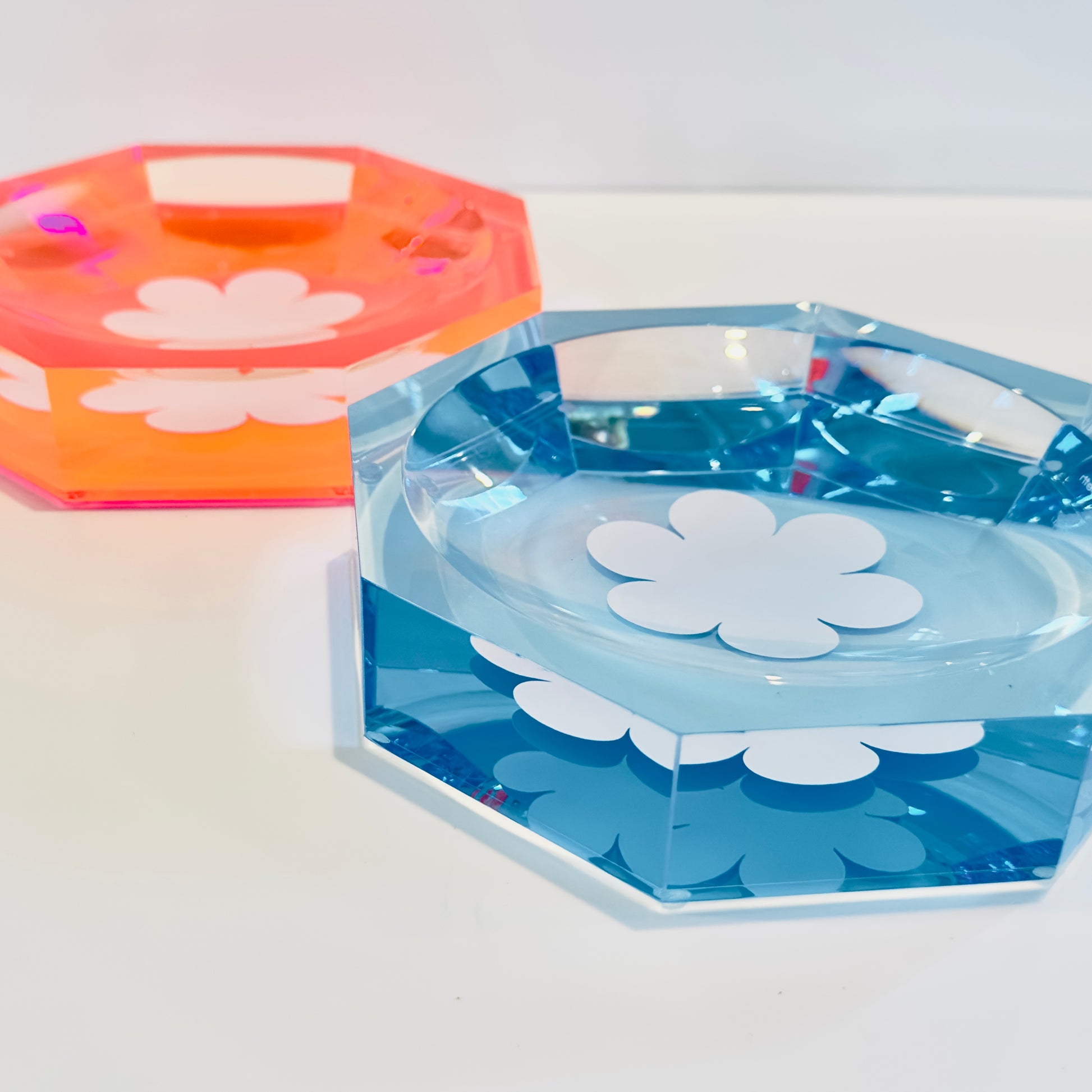 one blue and one pink acrylic dish with white floral design on a white background