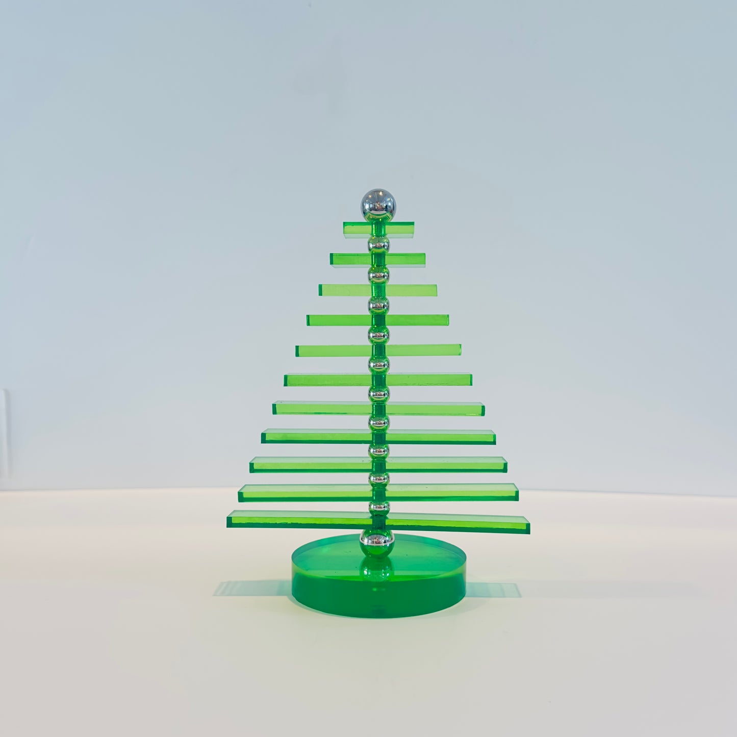Green acrylic Christmas tree with silver accents on a white background