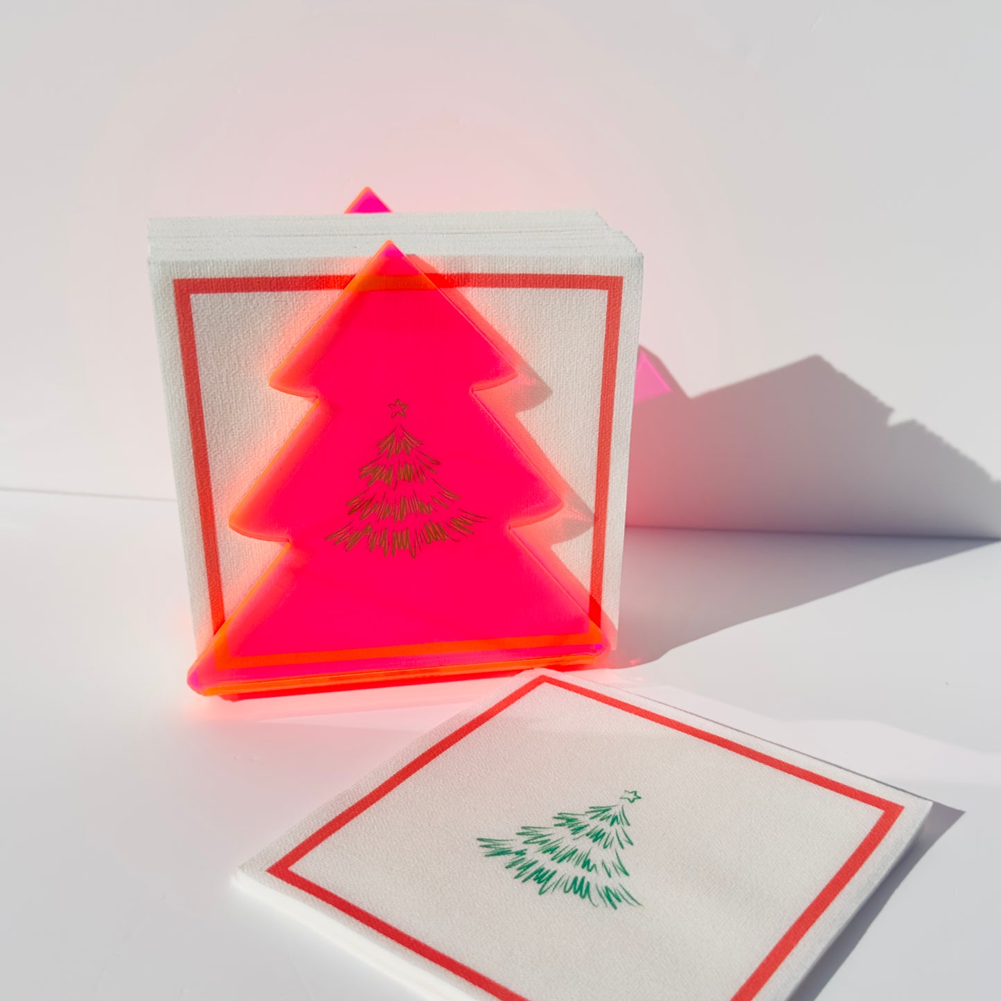 Neon pink Christmas tree shape on a white surface