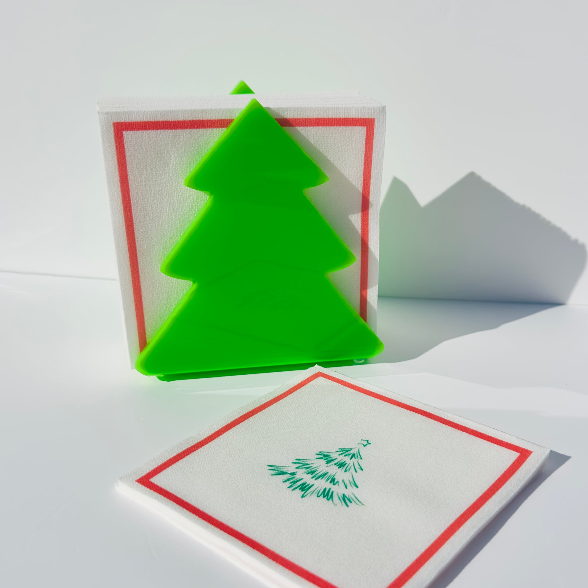 Green Christmas tree-shaped object on a white table with napkins in front