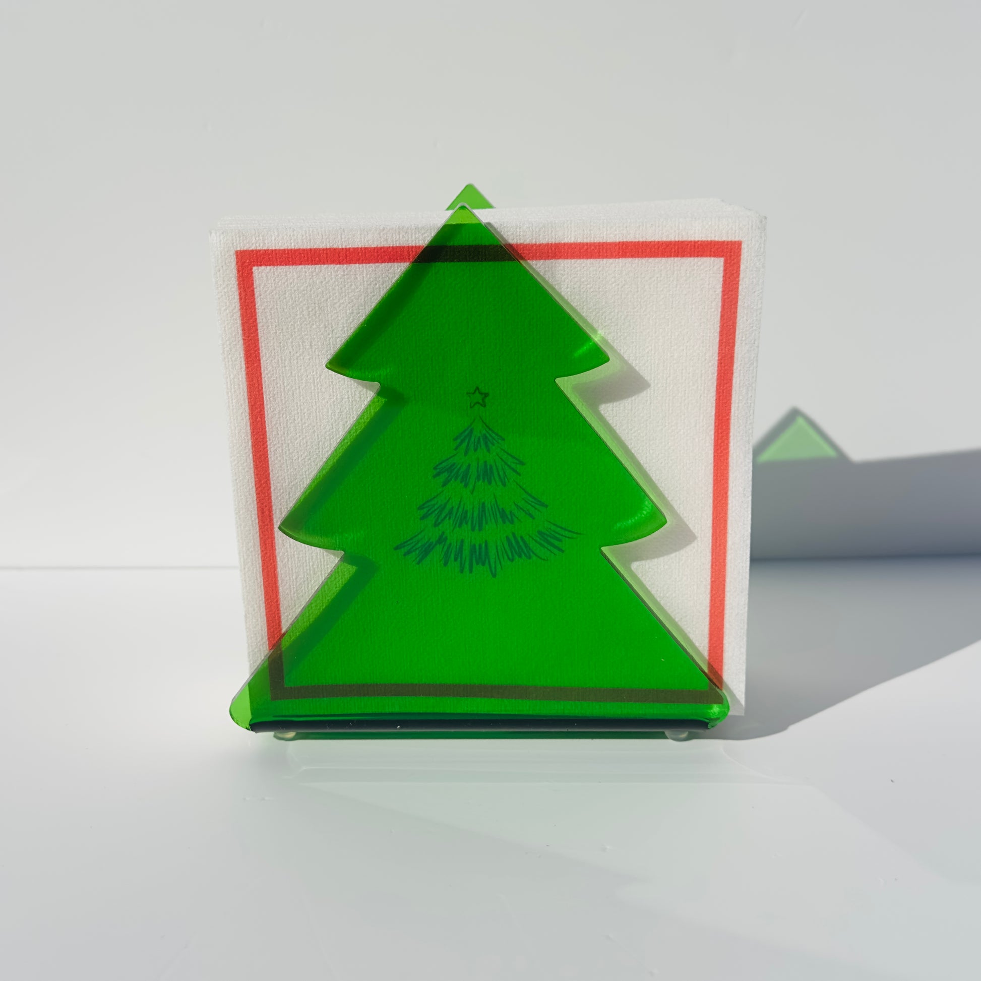 Green tree-shaped object on a white surface with white napkins with red border