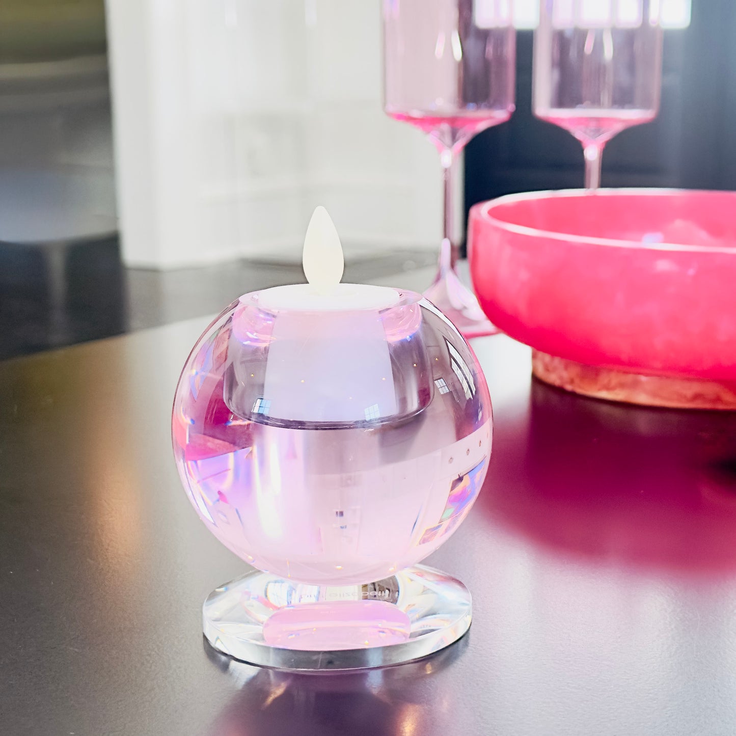 Small crystal candle holder with a white votive candle inside and sitting on a reflective table