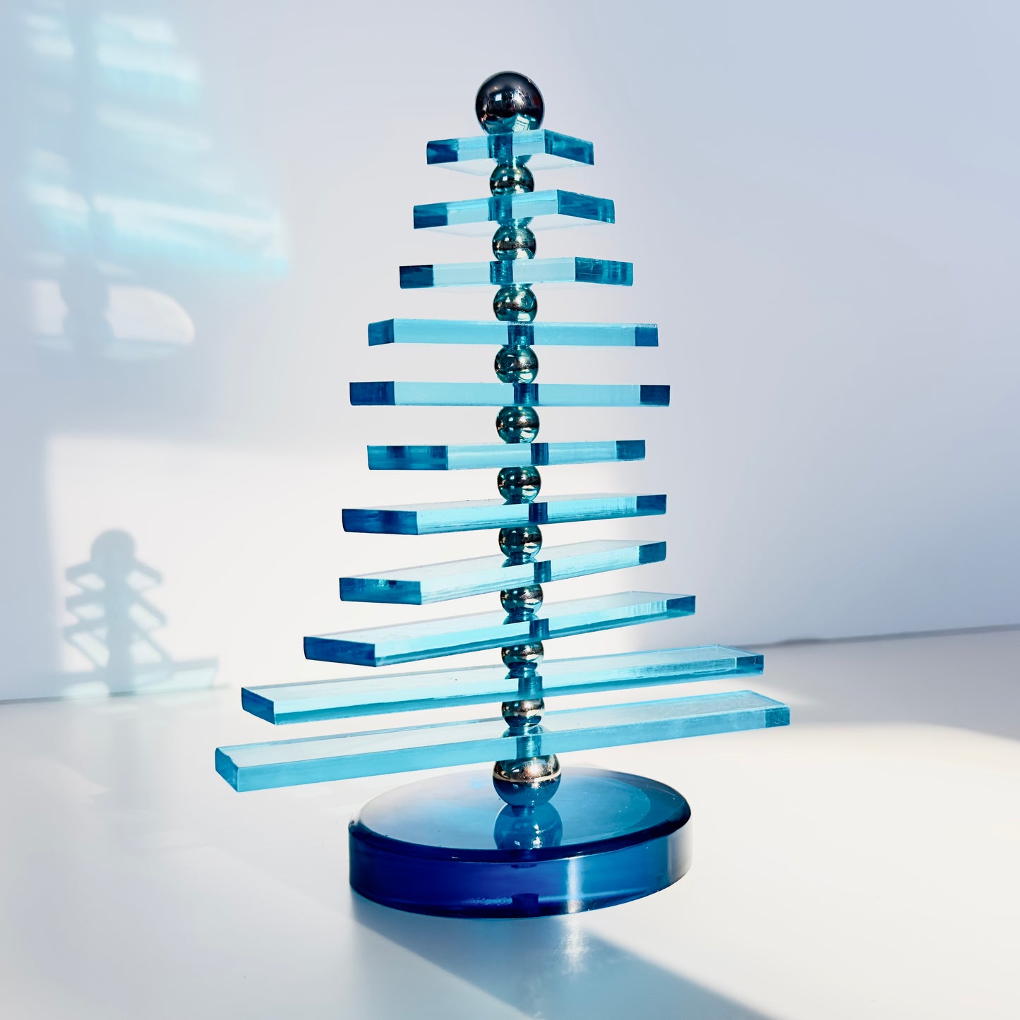 Blue acrylic sculpture on a white surface with a light gray background