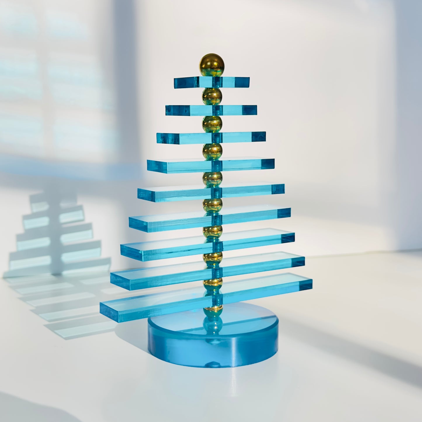 Blue and gold geometric tree sculpture on a white background