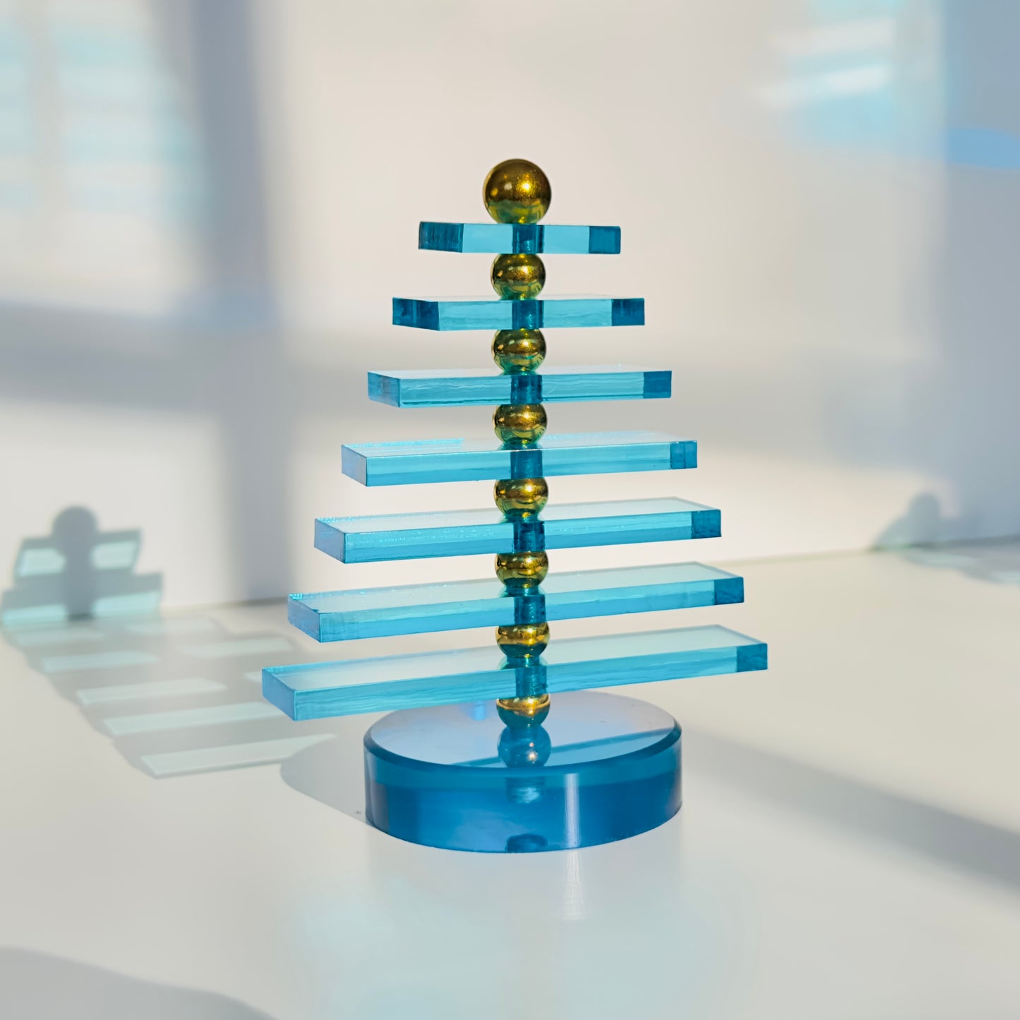 Blue and gold geometric tree sculpture on a white surface