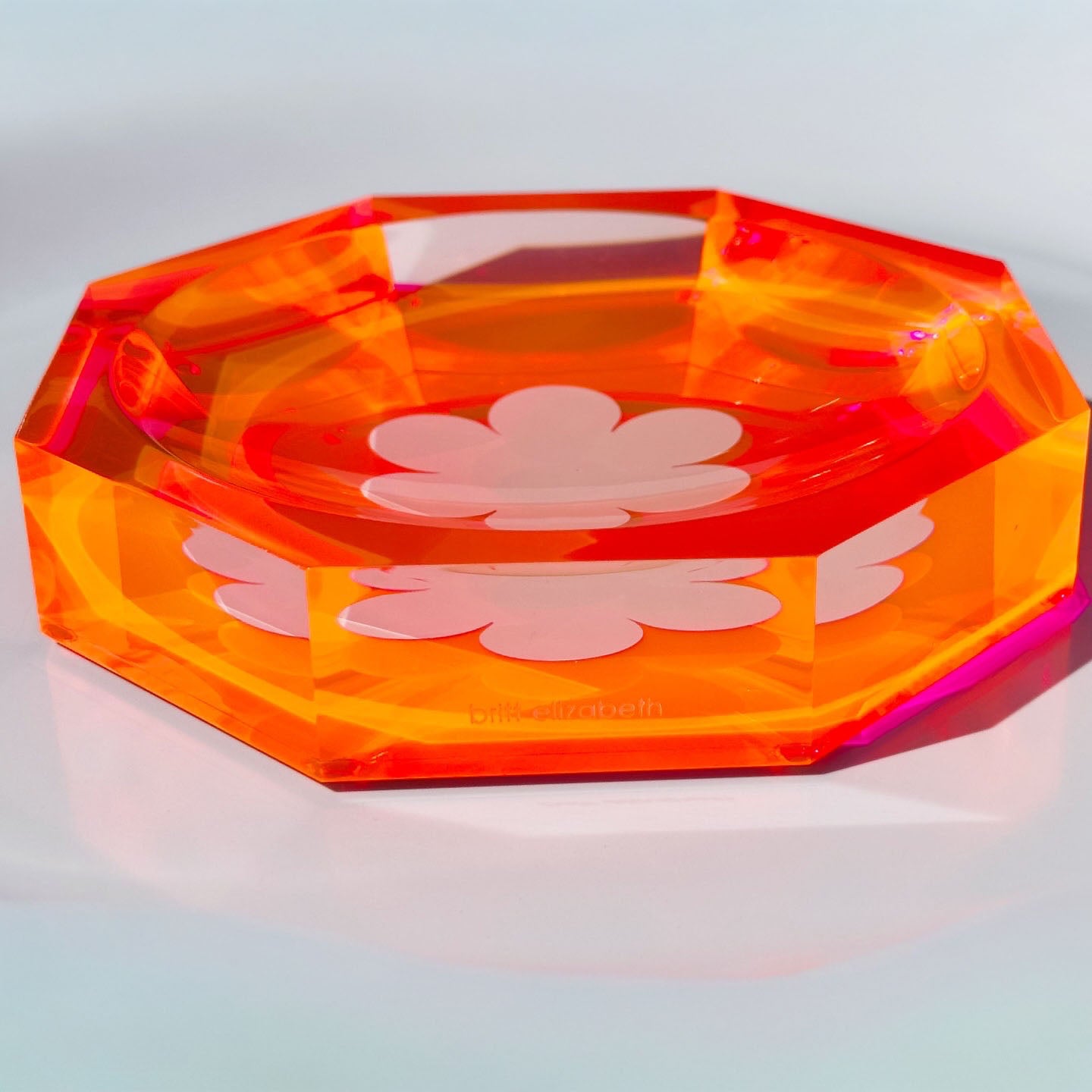 Octagonal orange and pink acrylic dish with floral design on a light gray background