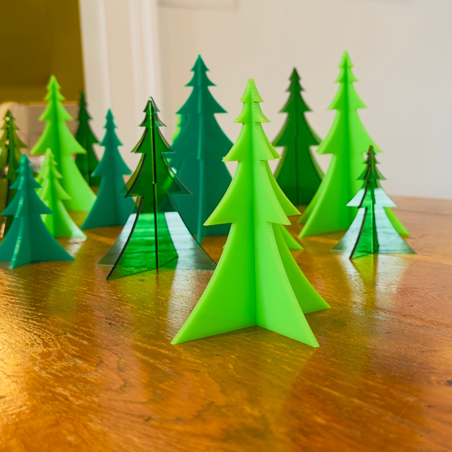Set of green acrylic trees on a wooden surface